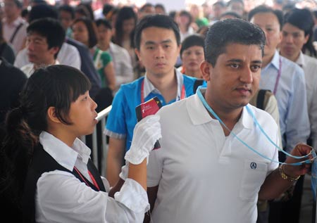 A staff member checks a visiter's body temperature during the third phase of the 105th Canton Fair in Guangzhou, capital of south China's Guangdong Province, on May 3, 2009. 