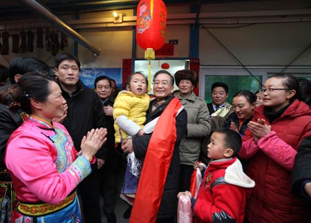 Chinese Premier Wen Jiabao (C) holds a girl in arms during his visit to the residents in Yingxiu Township of Wenchuan County, southwest China's Sichuan Province, on January 25, 2009. Wen Jiabao came to the quake-hit counties of Beichuan, Deyang and Wenchuan in Sichuan Province on January 24 and 25, celebrating the Spring Festival with local residents.