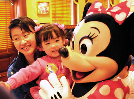 Song Xinyi (C), a girl who was crippled in the 5.12 massive earthquake in southweat China's Sichuan Province, has a photo taken with 'Mickey' at the Disneyland in Hong Kong, China, on February 10, 2009. Three disabled youngsters from Sichuan who are receiving artificial limb rehabilitation treatment in Hong Kong visit Disneyland on Tuesday. 