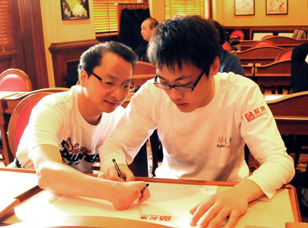 Gong Guilin (R), a boy who was crippled in the 5.12 massive earthquake in southweat China's Sichuan Province, learns how to draw 'Mickey' with the help of an employee (L) at the Disneyland in Hong Kong, China, on February 10, 2009.