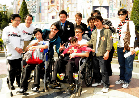 Youngsters who were crippled in the 5.12 massive earthquake in southwest China's Sichuan Province and their families pose for a group photo with employees at the Disneyland in Hong Kong, China, on February 10, 2009.