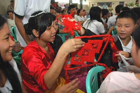 Philippine students receive a Chinese knot as a gift from their Chinese companions at the Raja Suliman Science And Technology High School in Manila, the Philippines, on January 15, 2009. Invited by Philippine President Gloria Macapagal-Arroyo, a group of 100 children who survived a devastating earthquake in China last May arrived in the Philippines on Sunday for a week-long trip.