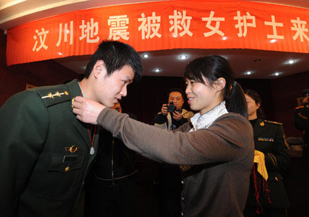 Duan Zhongying (R), a survivor of last year's Sichuan earthquake, gives an amulet to Yu Feng, one of the firemen who rescued her, in Yangzhou, east China's Jiangsu Province, on March 17, 2009. 