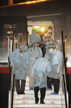 Mexican medical workers cald in surgical suits stand on the gangway of Mexican charter flight at Hong Kong International Airport in Hong Kong, south China, May 6, 2009. 