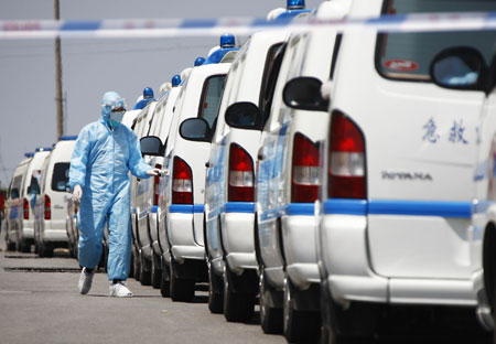 A medical staff member walks past ambulances carrying Mexican nationals in Shanghai, east China, on May 5, 2009. A Mexican chartered plane carried 43 quarantined Mexicans and 34 others back to Mexico Tuesday. Those on the plane included 43 crew members and passengers on board the AM098 and 34 others who worked and lived in China but were not under quarantine. 