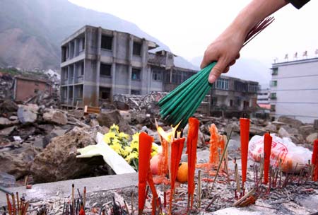 A person lits Chinese traditional insenses when condoling victims of the last May's big earthquake in site of former Beichuan County Town, southwest China's Sichuan Province, on May 1, 2009. 