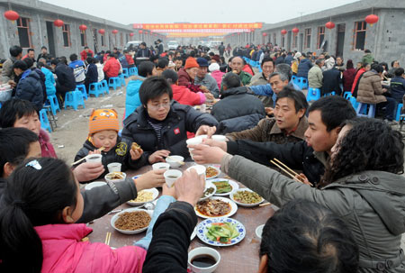 Villagers celebrate for moving to permanent dwellings in front of their new residences at Anren Village of Mianzhu City, southwest China's Sichuan Province, on January 18, 2009. A total of 332 Anren villagers whose houses collapsed or dilapidated during the May 12 massive earthquake last year feasted on Sunday to celebrate the resettlement. [Xinhua]