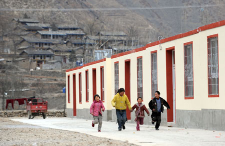 Kids play outside newly-built houses at Songba village in Wenxian County of Longnan City, northwest China's Gansu Province, on January 23, 2009. A total of 66 quake-affected families at Songba village moved into the 216 new houses before the Chinese Lunar New Year.