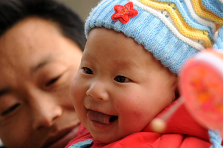 Baby Gao Zhen smiles in his father' s arms in Shuicaogou Village in Wenxian County of Longnan City, northwest China's Gansu Province, on January 24, 2009. Gao Zhen with the nickname Zhensheng which means born on the day of the earthquake happened was dressed in new clothes to celebrate the coming Spring Festival.