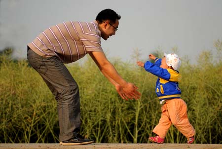 Li Yongbing plays with his son Li Zihao in a wheat field in Fuxin Township, Mianzhu City, Sichuan Province, southwest China, on May 3, 2009.