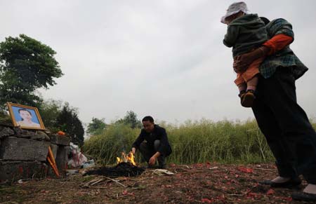 Li Yongbing and his relatives mourn for his deceased wife in Fuxin Township, Mianzhu City, Sichuan Province, southwest China, on May 1, 2009. Li Yongbing, 28, is a teacher at a primary school at Qingping Village in Mianzhu City. His wife Wang Qin, who was also his colleague, died in the May 12 earthquake last year and left their little son Li Zihao behind. In the first few months after the disaster, Li Yongbing worked as a volunteer.