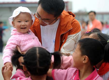 Li Yongbing holding his son chats with his students in Fuxin Township, Mianzhu City, Sichuan Province, southwest China, on May 4, 2009.