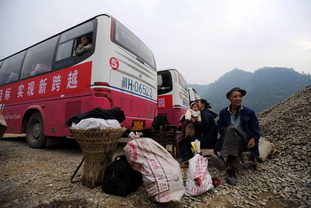 Earthquake survivors wait for buses as they prepare to leave for new houses as part of a relocation project in Qingchuan County, southwest China's Sichuan Province, on May 6, 2009. 