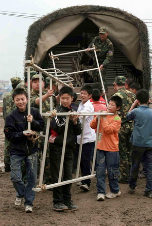 Pupils help unload relief goods delivered by military forces from east China's Shangdong province to Beichuan county, southwest China's Sichuan Province on May 6, 2009.