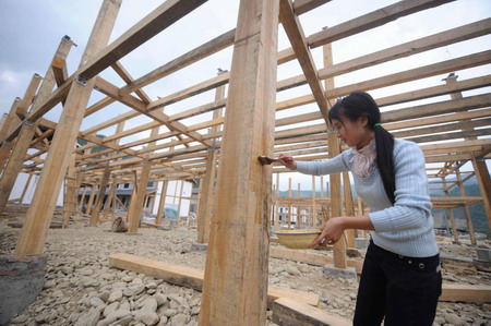 A villager paint the columns at a construction site of houses in Qingchuan county, southwest China's Sichuan Province, on May 6, 2009. 