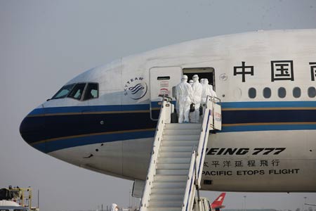 Inspectors walk aboard the chartered plane from Mexico to check the health of Chinese citizens from Mexico after the plane arrived in Shanghai on May 6, 2009. The chartered plane sent to fetch Chinese citizens from Mexico arrived in Shanghai on Wednesday afternoon, with 98 passengers and 21 crew members on board.