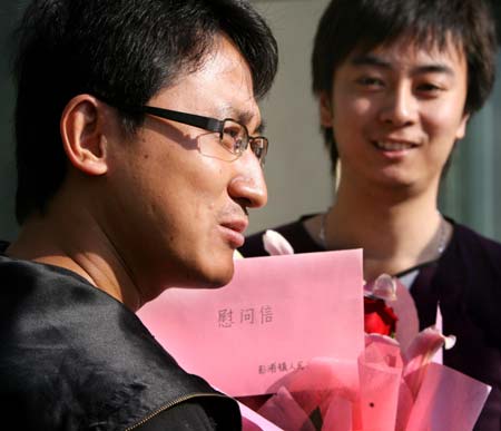 A Chinese passenger (L) from the Mexico City-Shanghai flight AM098, where a Mexican man was confirmed to be infected with influenza A/H1N1, receives flowers and a letter as the quarantine ends in Shanghai, east China, May 7, 2009. Chinese health authorities on Thursday started lifting a seven-day quarantine on passengers who took the same flight with the Mexican man.