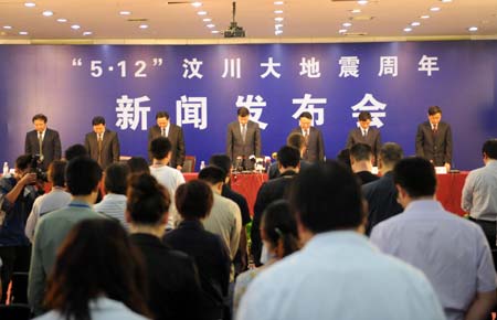 Attendees pay a silent tribute to the earthquake victims before a press conference presenting the current situation of the recovery and rebuilding operation in Sichuan Province, the epicenter of the May 12 magnitude-8.0 earthquake, in Chengdu, capital of southwest China's Sichuan Province, on May 7, 2009.