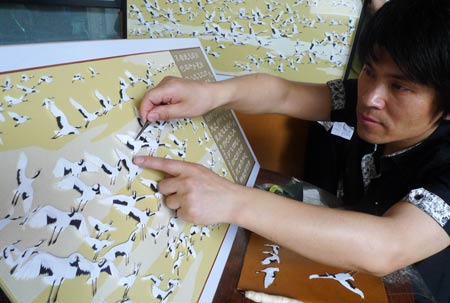 Jiang Wenhan (C) sticks his paper cranes to the board at his home in Beijing, capital of China, on May 7, 2009. Jiang, an ordinary Beijing citizen, made 999 paper cranes in almost half a year, to commemorate the victims of the Sichuan earthquake on May 12 last year.