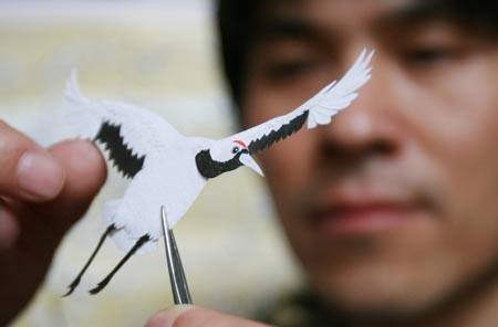 Jiang Wenhan (C) shows his paper crane works at his home in Beijing, capital of China, on May 7, 2009. Jiang, an ordinary Beijing citizen, made 999 paper cranes in almost half a year, to commemorate the victims of the Sichuan earthquake on May 12 last year.