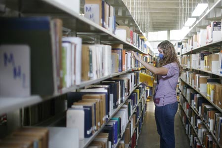 A student wearing a mask browses the bookshelf at the National Autonomous University of Mexico (NAUM) in the Mexico City on May 7, 2009.