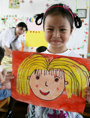 A kid shows her drawing of her mother, at Yixiu kindergarten in Suzhou, east China's Jiangsu Province, May 8, 2009, to celebrate the Mother's Day, which falls on May 9 this year. (Xinhua/Hang Xingwei)