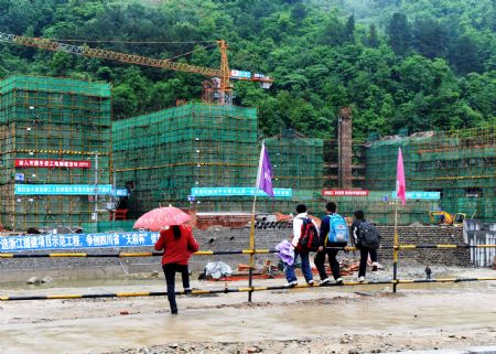 People look at under-construction buildings in Qiaozhuang Town of Qingchuan County, southwest China's Sichuan Province, on May 9, 2009. Qingchuan County seat Qiaozhuang Town, heavily hit by last year's May 12 earthquake, will be reconstructed on the same site, said a provincial official on May 7. 