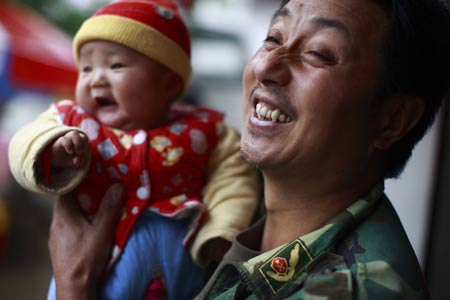 Shi Guangwu smiles while carrying his grandson at Zaoshu village of Qingchuan County, southwest China's Sichuan Province, on May 9, 2009.
