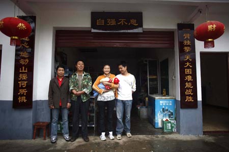 Shi Guangwu's family members take a group picture in front of their store at Zaoshu village of Qingchuan County, southwest China's Sichuan Province, on May 9, 2009.
