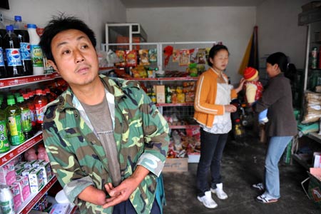 Shi Guangwu (L) waits for the arrival of the truck with supplies at the gate of his store at Zaoshu village of Qingchuan County, southwest China's Sichuan Province, on May 9, 2009.