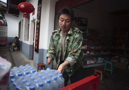Shi Guangwu carries water for his store at Zaoshu village of Qingchuan County, southwest China's Sichuan Province, on May 9, 2009.