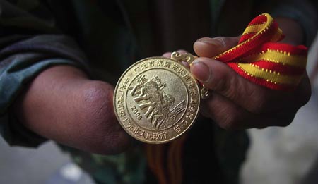 Shi Guangwu shows his medal for model citizen of Guangyuan City after quake reconstructions, at Zaoshu village of Qingchuan County, southwest China's Sichuan Province, on May 9, 2009.