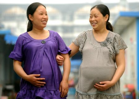 Zhao Xiaoqing (L) and another pregnant woman walk between prefab rooms of Mum's Home, a psychological assistance institution in Dujiangyan City, southwest China's Sichuan Province, on May 8, 2009. 