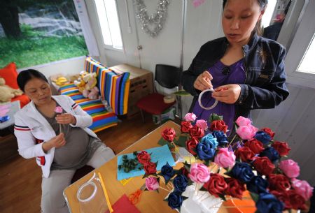 Zhao Xiaoqing (R) and another pregnant woman make paper flowers at Mum's Home, a psychological assistance institution in Dujiangyan City, southwest China's Sichuan Province, on May 8, 2009. 