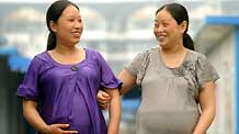Zhao Xiaoqing (L) and another pregnant woman walk between prefab rooms of Mum's Home, a psychological assistance institution in Dujiangyan City, southwest China's Sichuan Province, on May 8, 2009.