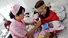 Zhang Hongmin (R) carries her newborn twins at a prefab hospital in Qingchuan, southwest China's Sichuan Province, on May 10, 2009.