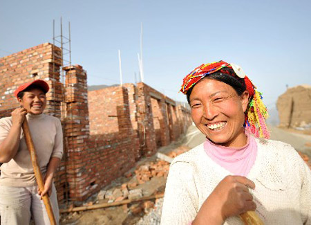 Photo taken on April 19, 2009, shows two villagers in Maigongshan Village, Tielou Township, Wenxian County, Gansu Province, smile while rebuilding their new houses.