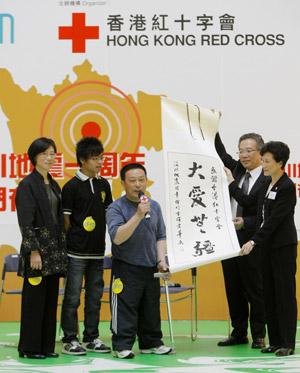 Yang Huabing (C) presents his calligraphy work, meaning 'Great love has no boundaries', to the Hong Kong Red Cross at a photo exhibition in Hong Kong, south China, on May 11, 2009. 