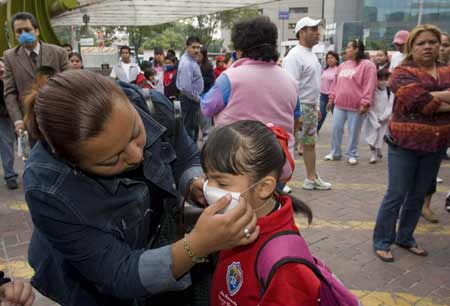 A woman helps her daughter wear the mask before she walks to classroom at a primary school in Mexico City, capital of Mexico, on May 11, 2009. Most of Mexican pre-school educational institutions as well as primary and secondary schools resume classes May 11 after days of closure due to the influenza epidemic. 