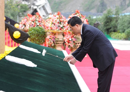 Chinese President Hu Jintao places a white chrysanthemum in front of a commemorative wall of the earthquake during the commemorative service to mark the first anniversary of May 12 Earthquake in Yingxiu Township of Wenchuan County, southwest China's Sichuan Province, on May 12, 2009. 