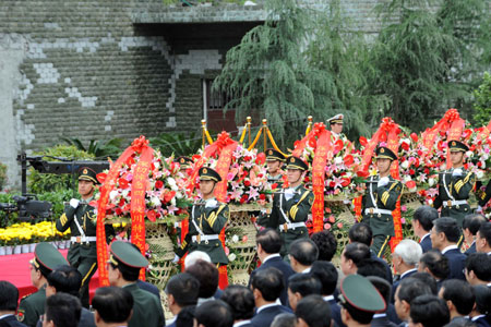 Guards of honor present floral baskets to the symbolic clock during the ceremony to mark the first anniversary of May 12 Earthquake in Yingxiu Township of Wenchuan County, southwest China's Sichuan Province, on May 12, 2009.