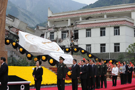 People present flowers during the commemorative service to mark the first anniversary of May 12 Earthquake in Yingxiu Township of Wenchuan County, southwest China's Sichuan Province, on May 12, 2009.