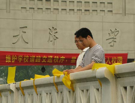 Voluteers fasten yellow ribbons on handrails outside Tianjin University in north China's Tianjin, on May 12, 2009. Volunteers tied thousands of yellow ribbons on buses, buildings and trees as a way to commemorate the victims of the May 12, 2008 Wenchuan earthquake. 