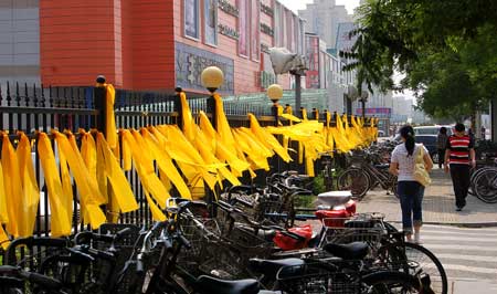 Pedestrians walk past fences tied with yellow ribbons on a street in north China's Tianjin, on May 12, 2009. Volunteers tied thousands of yellow ribbons on buses, buildings and trees as a way to commemorate the victims of the May 12, 2008 Wenchuan earthquake. 