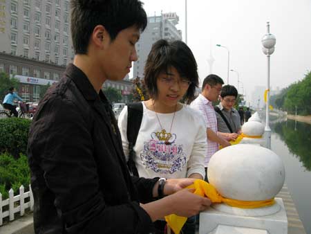 Volunteers tie yellow ribbons to handrails of a bridge in north China's Tianjin, on May 12, 2009. Volunteers tied thousands of yellow ribbons on buses, buildings and trees as a way to commemorate the victims of the May 12, 2008 Wenchuan earthquake.