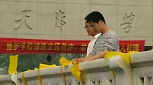 Voluteers fasten yellow ribbons on handrails outside Tianjin University in north China's Tianjin, on May 12, 2009. Volunteers tied thousands of yellow ribbons on buses, buildings and trees as a way to commemorate the victims of the May 12, 2008 Wenchuan earthquake.
