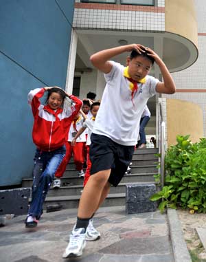 Students take part in a quake rescue drill at Jingcheng Experimental School in Hangzhou, capital of Zhejiang Province in east China, on May 12, 2009, China's first National Disaster Prevention and Reduction Day on the occasion of the first anniversary of the May 12, 2008 Wenchuan earthquake.