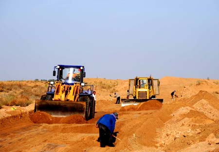 People manipulate bulldozers to work in Ulan Buh Desert of north China's Inner Mongolia Autonomous Region, on May 12, 2009. China starts to build the first road through the desert recently. With the length of 71.6 kilometres, the road will be put into use on September 30.