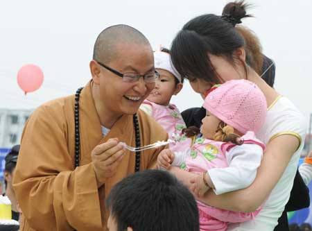 Monk Suquan feeds a baby with a piece of birthday cake at a school in Shifang City, southwest China's Sichuan Province, May 13, 2009.