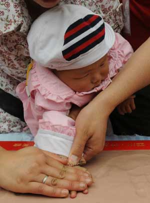 A baby is helped make a hand clay model during a vocational inclination test ceremony for the 'earthquake babies ' at a school in Shifang City, southwest China's Sichuan Province, on May 13, 2009. The Luohan (Arhat) Temple in Shifang took in all the lying-in pregnant women as the neighbouring Maternal and Child Care Service Center of Shifang was dilapidated by the earthquake on May 12, 2008. Since May 13 to August 7, 2008, a total of 108 infants had been born in the temple. 